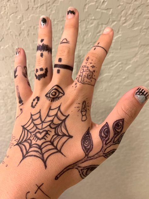 A hand with various doodles on it; including a heart-shaped spider web, a plant with eyes on the leaves, simple lava lamp and gun designs, and bands of different patterns on the fingers. Sharpie Hand Doodles, Sharpie Doodles, Grunge Tattoo, Pretty Hand Tattoos, Finger Tattoo Designs, Pen Tattoo, Sharpie Tattoos, Hand Doodles, Hand Drawings