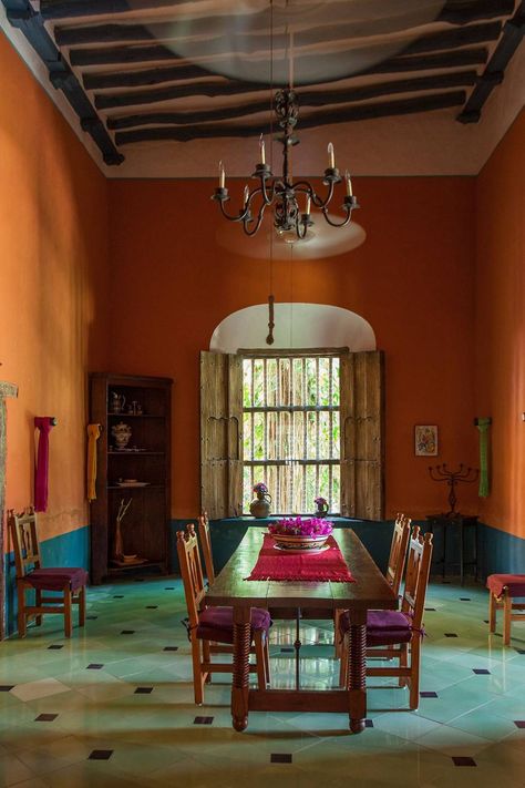 The main hacienda dining room is furnished with traditional Mexican furniture. The lower half of the room is painted a deep blue as a contrast to the orange walls.  [i][link url="https://www.rizzolibookstore.com/casa-mexico-home-merida-and-yucatan"]Casa Mexico: At Home in Merida and the Yucatan[/link] by Annie Kelly and photographed by Tim Street-Porter ([link url="http://www.rizzoliusa.com/"]Rizzoli[/link], £45).[/i] Mexican Style Dining Room, Mexican Dining Room, Mexico Interior Design, Mexican Home Interior, Vacation House Decor, Mexican Villa, Mexican Interior Design, Theme Restaurant, Mexican Interiors