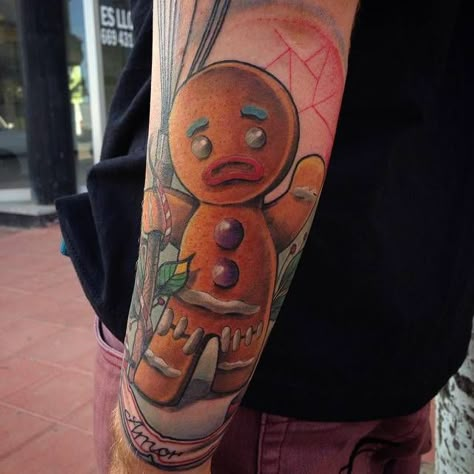 Tatuaje de la galleta de jengibre Jengi, de la saga de Shrek, en estilo neotradicional y situado en el antebrazo izquierdo. Shrek Gingerbread Man Tattoo, Gingerbread Man Tattoo, Bakery Tattoo, Shrek Gingerbread Man, Shrek Gingerbread, Shrek 2001, Tattoo Shop Interior, Man Tattoos, Community Tattoo