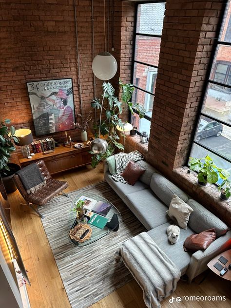 Old money, loft, apartment, vintage, retro, vibes, masculine, interior design, living room inspo, gray couch, grey sofa, glass coffee table, gray grey rug, leather chair, high cealing, unique wall art, plants in room, top down view, table decoration, shelf decoration, 1900s vibe, rich vibe, 80s, 90s, 70s, natural lighting Room Inspo Gray, Interior Design Open Floor Plan, Vintage Loft Apartment, Masculine Interior Design Living Room, Loft Entrance, Contemporary Loft Design, Plants In Room, Loft Living Room Ideas, Loft Art Studio