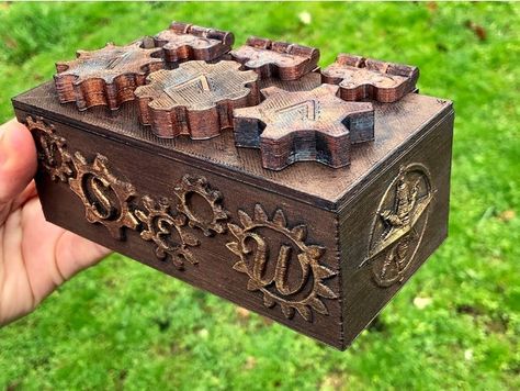 This box was inspired by lovidovi's Escape Room Puzzle Box- https://www.thingiverse.com/thing:3135034 So I am listing it as a remix, although it is completely redesigned to print on smaller printers and to not give away the combination as easily :-) Everything was printed at 0.3mm height except the hinges were 0.2mm. Finished all parts with metallic wax. Assembly is straightforward, just make sure that you tape the locks to the underside of the lid with the flat edges in a straight line, an Puzzle Box Design, Escape Box, Ender 3 Pro, Escape Room Ideas, Small Printer, Escape Room Puzzles, Puzzle Boxes, 3d Printing Business, Diy Puzzles