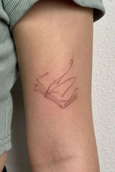 Exploring the World of Book Tattoos - Tweakbee Recipe Tattoo Ideas, Dragon Coming Out Of A Book Tattoo, Book Tattoo Minimal, Dinky Tattoos, Book Ish Tattoos, Book Mark Tattoo, Book Nerd Tattoo, Small Ethereal Tattoos, Turn The Page Tattoo