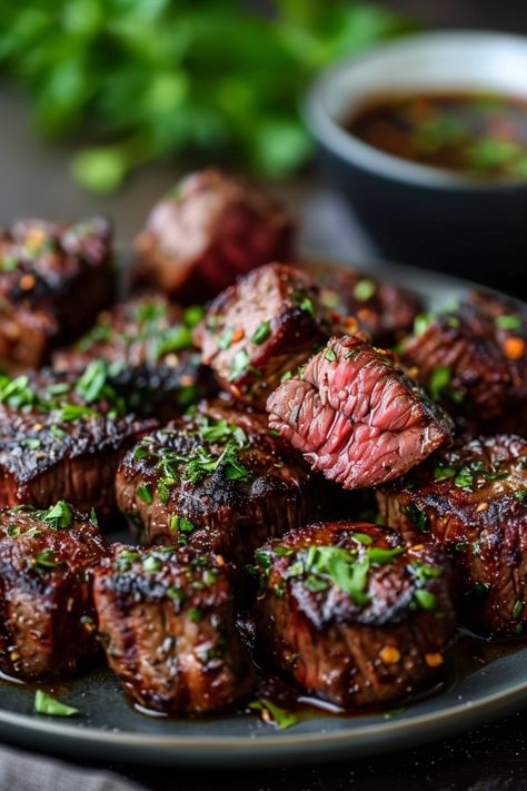 Grilled beef steak bites garnished with herbs on a plate, with a bowl of dipping sauce in the background. Air Fryer Steak Bites, Chamorro Recipes, Garlic Butter Steak Bites, Spicy Steak, Crispy Air Fryer Chicken, Butter Steak Bites, Air Fryer Vegetables, Frozen Steak, Steak Bites Recipe