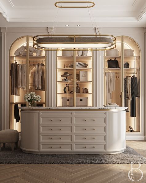 This elegant walk-in closet, designed by @base9studio, is a dream come true for fashion enthusiasts. With ample storage and stylish gold accents, the curved island vanity creates a luxurious focal point. The arched glass doors showcase the beautifully organized clothing and accessories, while the soft lighting and plush rug add a touch of warmth and sophistication. This closet is not just a functional space; it's a true statement of style and luxury. 😍✨ Explore more luxurious inspiration via... Walk In Wardrobe With Island, Elegant Walk In Closet, Walk In Wardrobe Luxury, Walk In Closet Island, Lux Closet, Wardrobe Design Modern Interiors, Elegant Dressing Room, Arched Glass Doors, Walk In Closet Luxury