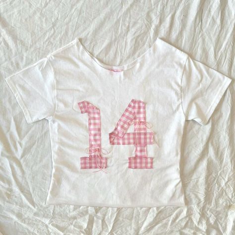 Custom handmade patchwork tees sizes S-L --Handmade 14 jersey cropped Tee (S) Super cute Hand stitched gingham 14 Jersey design w/pink bows detailing. One of a kind custom made! Prices vary depending on design/customs. (Made to order) Diy Letters On Shirt, Customized T Shirts, Embroidery Clothes T Shirts, Patchwork Tee Shirt, Patchwork T Shirt Diy, Diy Jersey Shirt, Patchwork Baby Tee, Decorating T Shirts, Patch Work Top