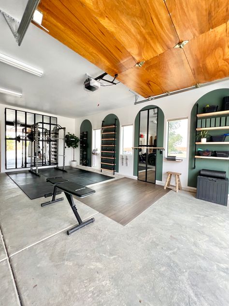 DIY home gym in a garage with green painted arches, large black framed mirror, a wall mounted weight rack, storage shelves, and ballet barre with dance floor. Cute Garage Gym, Yoga Studio In Garage, Garage Home Gum, Garage Makeover Gym, Garage Ballet Studio, Garage Turned Into Gym, Garage To Gym Makeover, Garage Gym Corner, Yoga Studio Garage