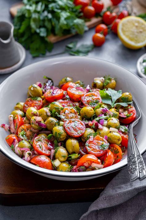 Discover the vibrant flavors of this refreshing Green Olive Salad, packed with fresh ingredients like tomatoes, onions, and herbs. This healthy and delicious salad is elevated by a tangy dressing made from lemon juice, sumac, and pomegranate molasses. Perfect as a side dish, light lunch, or potluck favorite, you'll love how the unique combination of ingredients creates a satisfying and unforgettable taste experience! Tomato And Olive Salad, Tomato Olive Salad, Super Salads Recipes, Green Olive Recipes, Olives Salad, Green Olive Salad, Unique Salad, Salad Lunch, Olive Salad