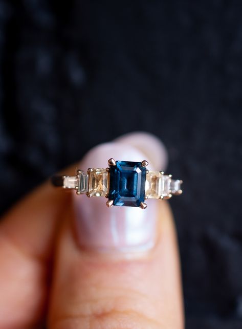 This custom emerald cut sapphire and diamond baguette engagement ring was designed for a client who met her fiancé on Sapphire Street. Accordingly, it was symbolic to include sapphire as the main stones in her engagement ring, dark blue for her center stone, and yellow sapphires because her favorite color is yellow. Wanting with an estate jewelry feel, we prong set baguette diamonds in descending order from the sapphire center stone, creating a silhouette with antique influences. #engagementring Sapphire And Baguette Diamond Ring, Vintage Engagement Rings Sapphire Antique Jewelry, Sapphire Emerald Cut Engagement Ring, Safire Rings, Emerald Cut Sapphire Ring, Asscher Cut Engagement Rings, Sapphire And Diamond Engagement Ring, Baguette Engagement Ring, Vintage Engagement Rings Sapphire