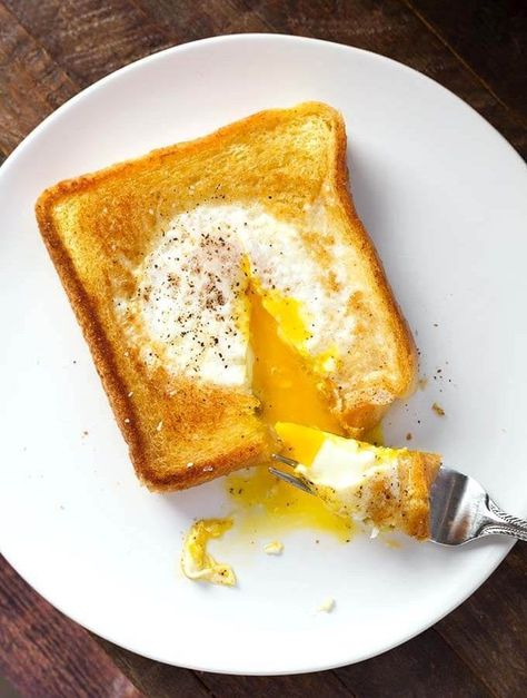 Egg in a Hole is a delicious piece of toast that has an egg soft cooked in the center, which has been cut out. This popular breakfast has many names, like Toad in a Hole, egg in a frame, egg in the basket, but this egg in toast recipe is delicious no matter what you call it! simplyhappyfoodie.com Dropped Eggs On Toast, Egg In A Hole Skillet, Bread With Egg In Middle, Toast With Egg In The Middle, Egg In The Hole, Bread Factory, Simply Happy Foodie, Egg In A Hole, Brunch Spread