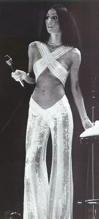 Cher, 1970s. White and sequin bell bottom pants with a criss cross top. Cher 70s, 1970s Outfits, Look Disco, 70s Mode, 70s Jumpsuit, Cher Outfits, Fest Temaer, Fashion 70s, Gene Kelly