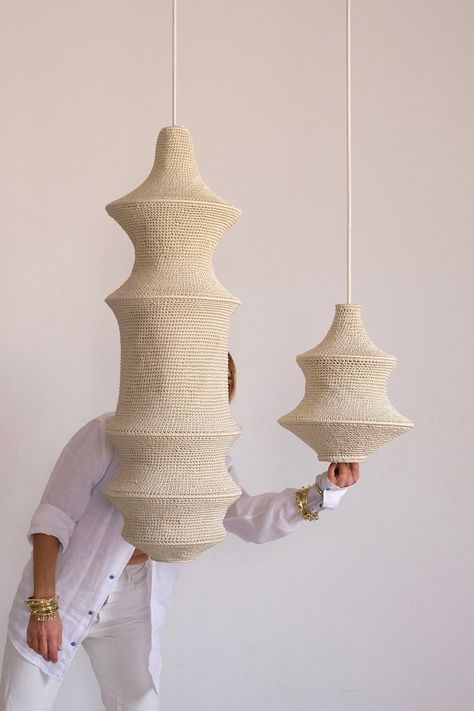 Two handcrafted crochet pendant lights suspended with a woman dressed in all white in the background. Modern Moroccan Design, Crochet Pendant, Crochet Lamp, Lighting Installation, Affordable Lighting, Crochet Mobile, Community Of Women, Internal Design, Handmade Lamps