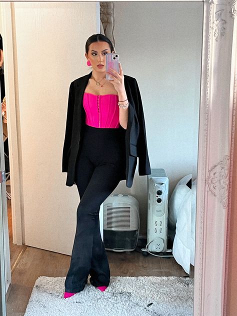 a mirror photo with a woman wearing black flared trousers from prettylittlething , bright pink pointed heels, bright pink corset and a black blazer draped over her shoulders. This is a night time outfit or a sophisticated outfit that would be best for date night , business parties and any sophisticated occasion. This look is perfect for a  date night or a night out in town or even a nice evening meal Pink And Black Formal Outfit, Black And Pink Style Outfit, Corset And Pants Outfit Formal, Black Outfit With Pink Accessories, Dark Pink And Black Outfit, Hot Pink Business Outfit, Purple Corset Top Outfit, Pink Top Black Pants Outfit, Hot Pink Corset Outfit