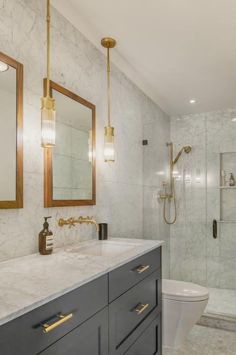 The master bathroom features a simple palette of walnut, brushed brass, marble, and dark gray cabinets. #masterbathroom #interiordesign #remodelideas #boardandvellum Brass Bathroom Ideas, Marble And Brass Bathroom, Dark Gray Cabinets, Grey Marble Bathroom, Brass Bathroom Fixtures, Grey Bathroom Cabinets, Dark Gray Bathroom, Condo Bathroom, Modern Condo