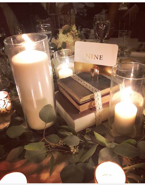 Literary themed wedding book centerpieces, eucalyptus and candles Books And Greenery Centerpieces, Book And Candle Centerpieces, Bookish Centerpieces, Book Tablescape, Green Gold Black Wedding, Long Candle Centerpiece, Candle Greenery Centerpiece, Book Centrepiece Wedding, Book Wedding Centerpieces