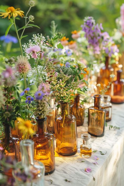 Elevate your wedding decor with a unique touch of the past. These vintage perfume bottles turned vases are filled with an array of herbs and wildflowers, perfect for a bohemian-themed celebration. 🌿🌼💐 A touch of nostalgia meets natural beauty for your special day. #WeddingInspiration #BohoWedding #CenterpieceIdeas #VintageDecor #FloralDesign #DIYWedding #EventStyling #WeddingFlowers Boho Wedding Table Flowers, Vintage Vases Wedding Centerpieces, Thrifted Wedding Vases, Vintage Table Decorations Wedding, 70s Wildflower Wedding, Dry Flower Wedding Decor, Dried Flower Table Decor, Wild Flowers Wedding Table, Spring Boho Wedding Decor