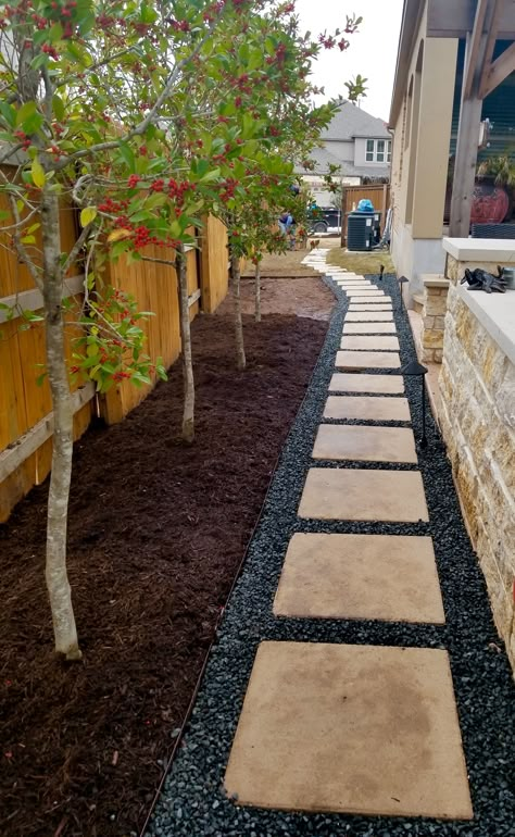 Residential design featuring black stone gravel, leuderstone pavers, mulch beds, Savannah Holly trees Gravel Fence Border, Black Stone Landscaping, Landscaping With Mulch, Savannah Holly, Black Mulch Landscaping, Driveway Edging Ideas, Mulch Yard, Holly Trees, Gravel Landscaping