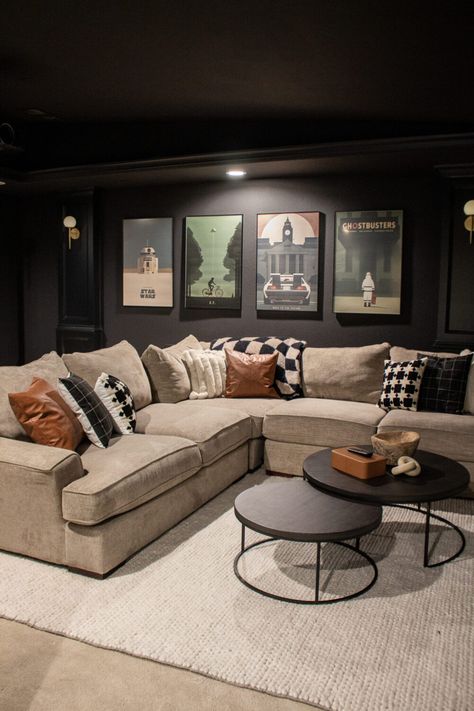 Tour this Vintage Modern Home Theater Decor with warm black walls and trim, vintage movie posters and lots of gold accents. Organic Modern Movie Room, Home Movies Theater, Black Walls Game Room, Black Accent Wall Movie Room, Movie Room With Sectional, Modern Home Movie Theater, Narrow Movie Room, Basement Ideas Dark Walls, Black Bonus Room Ideas