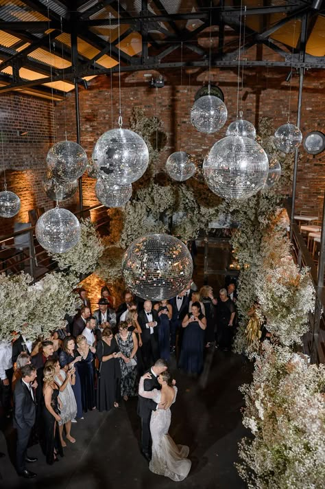 The couple's first-dance under the disco balls was to an acoustic version of “Rather Be” by Marc Scibilia that transitioned into the original Clean Bandit vers… Disco Ball And Chandelier Wedding, Disco Ball Decorations Wedding, Disco Balls At Wedding Reception, Nye Wedding Disco Ball, Wedding Reception Disco Balls, Moody Disco Ball Wedding, Disco Balls And Chandeliers Wedding, Hanging Disco Balls Wedding, Disco Ball Wedding Backdrop