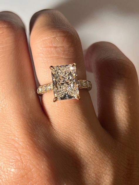 Our Juliana Engagement Ring features a breathtaking radiant cut diamond crafted in 18K yellow gold. This stunning center diamond is accentuated by a hidden halo and diamond prongs, adding a touch of mystique and enhancing the diamond's sparkle. The band is adorned with a three-row pavé setting, ensuring that every angle glistens with the brilliance of meticulously set smaller diamonds. Setting costs only. Refer to diamonds tab to choose your diamond Please allow 3-4 weeks for production. Different Shapes Of Engagement Rings, Emerald Shape Engagement Ring Gold, Radiant Cut Engagement Ring With Band Gold, Gold Ring Marriage, The Most Beautiful Engagement Ring, Wedding Rings Radiant Cut Gold, Radiant Cut Engagement Ring Yellow Gold, Gold Band Big Diamond Engagement Ring, Square Diamond Ring Gold