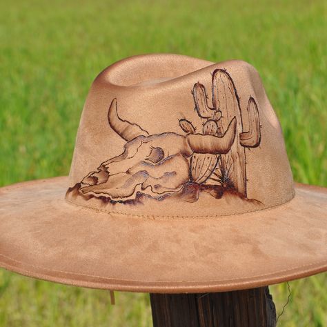 🔥 Saddle up in style with this one-of-a-kind, hand-burned south western fedora! 🤠 Featuring a bold desert design with a skull and cactus 🌵, this hat is perfect for adventurers and trendsetters alike. Every detail is uniquely crafted to stand out in any crowd. Custom hats for those who live wild & free! 🦬 #HandcraftedHats #WesternStyle #DesertVibes #CustomFedora #CowboyFashion #BohoChic #HatArt #BurnedArt #WesternWear #RanchLife Burnt Hat, Cactus Hat, Desert Design, Painted Hats, Hand Burn, Desert Vibes, Wild Free, Ranch Life, Cowboy Style