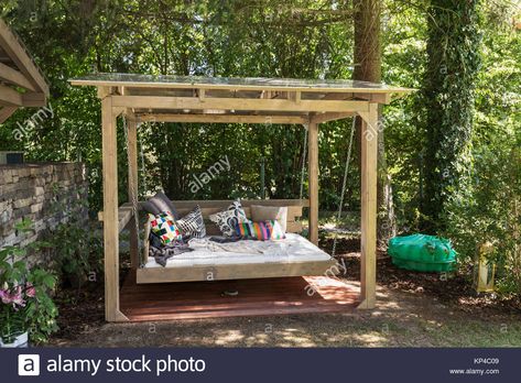 Download this stock image: Big swing outdoor bed. Chaise longue in the garden in the pergola. Garden bed with pillows. Big outdoor bed for sunbathing and rest. Four garden bed. - KP4C09 from Alamy's library of millions of high resolution stock photos, illustrations and vectors.