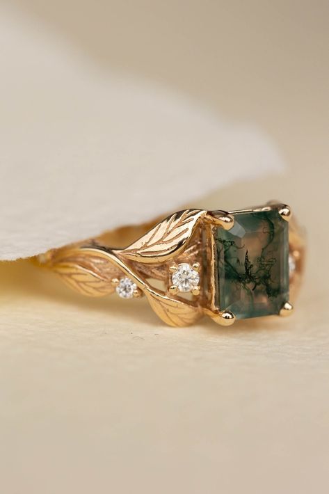 Discover the Clematis engagement ring, a handcrafted solid gold band featuring a stunning emerald cut gemstone with a modern twist. Inspired by nature, this alternative engagement ring is perfect for those seeking unique beauty. Choose from a variety of gemstones, including moss agate. Learn more at www.edengardenjewelry.com or contact us at info@edengardenjewelry.com for assistance.