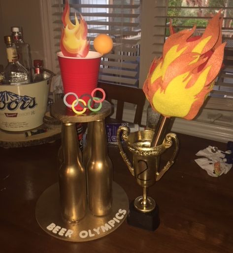 Homemade Beer Olympics trophy and torch. 2nd trophy is from the Dollar Store Beer Olympics Trophy, Olympic Trophy, Beer Olympics Shirts, Drunk Olympics, Camp Olympics, Diy Trophies, Beer Pong Trophy, Homemade Trophies, Beer Olympics Party