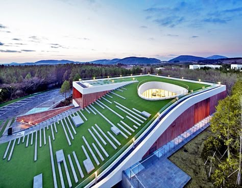 Sloping Green Roof Tops Submerged Multipurpose Hall on Jeju Island Amphitheater Architecture, Green Roof Building, Big Architects, Multipurpose Hall, Roof Tops, Commercial And Office Architecture, Green Roofs, Roof Architecture, Building Roof