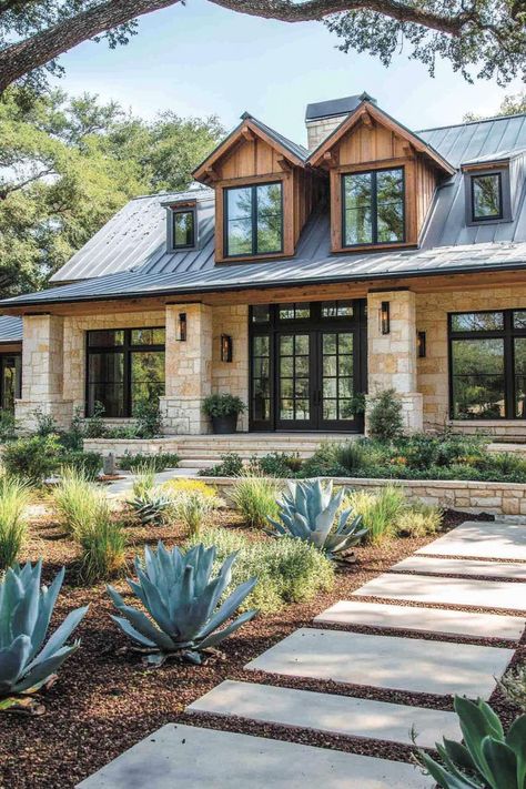 Modern farmhouse with stone exterior and lush greenery. Rustic modern farmhouses — where vintage vibes shake hands with modern comfort, sparking interior bliss! Hill Country Home Interior, Farmhouse With Rock Exterior, Texas Farmhouse Aesthetic, Brick Stone Board And Batten Exterior, Modern Brick Farmhouse, Rustic Stone House Interior Design, Exterior Mixed Materials, Stucco And Rock Exterior Home, White Rock House Exterior