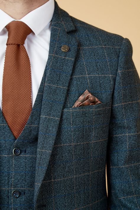 Show up in style with the blue Scott three piece suit. This vintage inspired suit draws inspiration from old age country tweeds, featuring a subtle check laid upon a durable heavyweight fabric, making it ideal for imitating that suave Peaky Blinders style. Character is added with the navy velvet contrast pocket trims and an eye-catching orange paisley pocket square peeking through the top pocket. Model wears size 40R blazer, 40R waistcoat & 34R trousers. Features Slim fit Single-breasted Notch l Non Traditional Suits For Men, Navy Suit With Vest, Blue Suit With Burnt Orange Tie, Groom Suit Charcoal Grey, Autumn Suit Men Wedding, All Blue Suit, Wedding Suits Groom Navy Blue, Double Breasted Tweed Suit, Vintage Tweed Suit