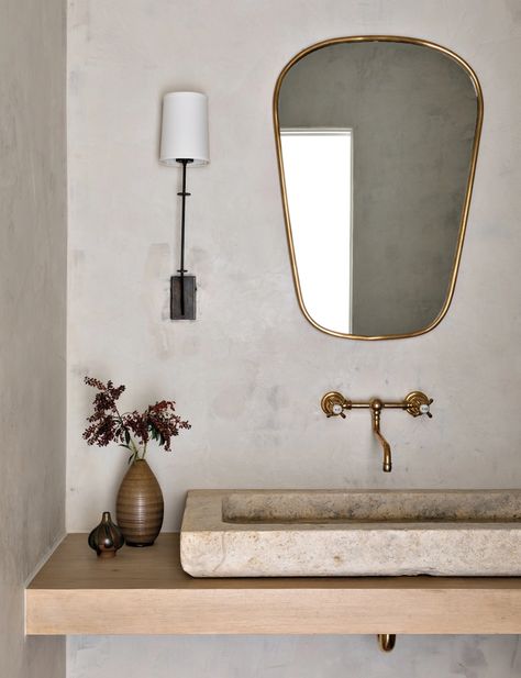 Limewash paint from Portola Paint & Glazes adds an aged quality to the powder room walls. The more traditional fixtures and furnishings, such as the unlacquered brass Waterworks faucet, the vintage limestone sink from Ancient Surfaces in New York, O’Lampia sconce and a vintage Italian mirror from 1stdibs break from the rest of the home’s modern silhouettes. Katie Hodges Design, Limestone Sink, Portola Paint, French Limestone, Luxe Interiors, Residential Interior Design, California Homes, Residential Interior, Interior Design Firms