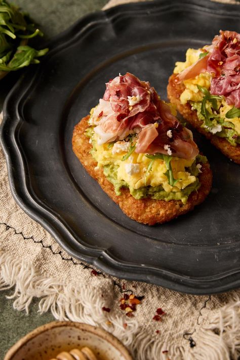 Introducing my Hashbrown Avocado Toast with Prosciutto—a delicious and satisfying breakfast or brunch option. This dish combines crispy hashbrowns, creamy avocado, prosciutto, arugula, and crumbled feta, all perfectly complemented by a drizzle of honey Arugula Avocado Toast, Eggs And Prosciutto Breakfast, Hashbrown Breakfast Aesthetic, Delicious Brunch Ideas, Avocado Toast On Hashbrown, Yummy Brunch Recipes, Brunch Items Easy, Avocado Hashbrown Toast, Late Brunch Ideas