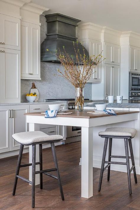 A white kitchen island is fitted with an extended dining table seating black oak counter stools at a wood countertop. Extending Kitchen Island, Cobalt Blue Kitchen, Island Extension, White Marble Kitchen Island, Blue Kitchen Island, Marble Kitchen Island, Florida Interior Design, Geometric Kitchen, White Marble Kitchen