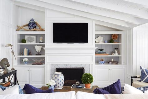 Chic living room features a sloped ceiling over a flat screen tv and white dentil fireplace mantle accented with carrera marble flanked by built-in bookshelves with backs of shelves lined with gray shiplap trim. Built In Around Fireplace, Marble Room, Fireplace Bookshelves, Shiplap Ceiling, Built In Shelves Living Room, Living Room Built Ins, White Shiplap Wall, Slanted Ceiling, Shiplap Fireplace