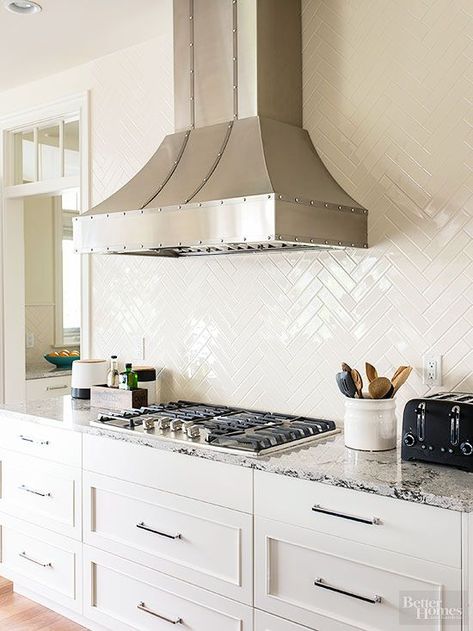 Glossy tiles -- basic subway tile in a herringbone pattern -- cover the entire wall behind the vent hood for a high-impact, low-maintenance backsplash.: Herringbone Kitchen Backsplash, Gorgeous White Kitchen, Kitchen Backsplash Tile Designs, Herringbone Kitchen, Backsplash Tile Design, White Kitchen Backsplash, White Tile Backsplash, Herringbone Backsplash, Design Assistant