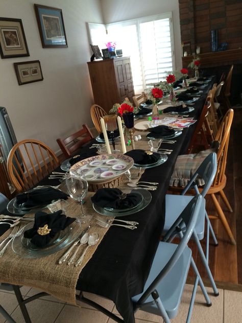 PASSOVER TABLESCAPE.  Used burlap runners on black tablecloths, tree cookies (sliced pieces of tree trunks), flowers in small milk bottles and silver. "Rustic and Sterling" tablescape. Black Table Cloth With Brown Runner, Black Tablecloth With Burlap Runner, Black And Burlap Table Setting, Passover Tablescapes, Burlap Table Settings, Parties Aesthetic, Senior Tea, Table Runner Ideas, Birthday Gala