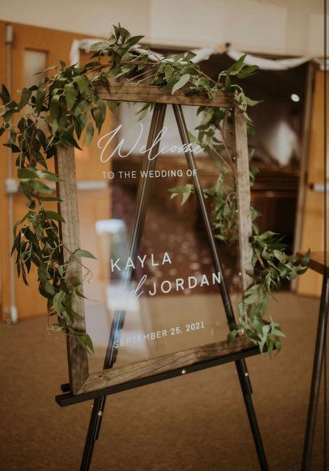 Make a statement by greeting your guests warmly with this stylish acrylic wedding welcome sign. This custom designed framed in a dark wood finish makes for a nice addition to a rustic Boho decor. The sign is available in an array of sizes and frame options. Wedding Signs Clear, Welcome To My Wedding Sign, Welcome To Our Wedding Wood Sign, Glass Signs For Wedding, Wedding Glass Welcome Sign, Clear Welcome Sign Wedding, Picture Frame Welcome Sign Wedding, Wedding Signs With Greenery, Floating Frame Wedding Sign