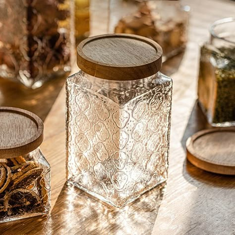 Introducing the Square Embossed Glass Storage Jar - a vintage-inspired, large capacity container perfect for storing a variety of items. Its strong sealing properties and intricate design elevate both your organization game and home decor. Upgrade your space with this timeless and elegant piece today! DETAIL - Item No: 202305ST53 - Material: Glass + Wood - Package include: 1/Pack