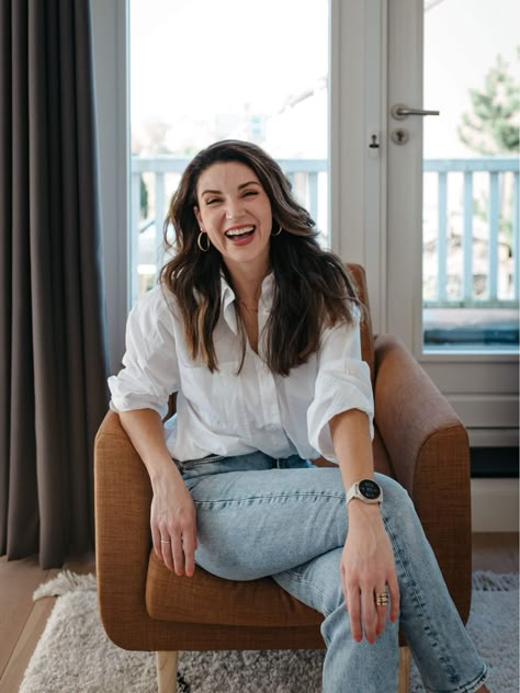 Woman is sitting in a brown leather chair laughing dressed in a white blouse and blue jeans, a classic look for a business branding photoshoot in her home in Amsterdam Casual Business Headshots, Home Branding Photoshoot, Business Casual Photoshoot Outfits, City Branding Photoshoot, Office Photoshoot Ideas Work Spaces, Female Business Aesthetic, Business Photo Shoot Poses, Branding Photo Outfits, Branding Session Outfit