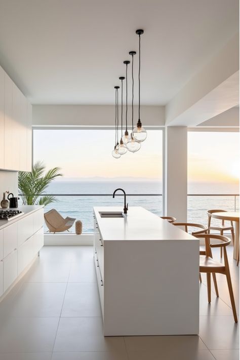 Minimalist white coastal kitchen with glass globe pendant lights and sunset view Modern Minimalist Coastal Kitchen, Kitchen For Beach House, Modern Coastal Pendant Lighting, Kitchen Coastal Modern, Scandinavian Coastal Interior, Coastal Lighting Fixtures Beach Houses, Modern Beach House Kitchen, Beachy Kitchen Ideas, Coastal Renovation