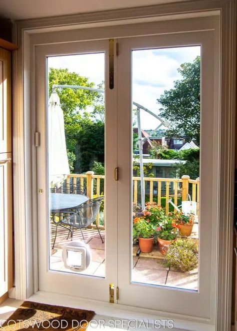 Stunning wooden bifolding doors with full double glazing, installed in a contemporary kitchen. The doors are fitted on a clever track system which enables them to slide fully open – ideal for opening up the kitchen to the garden on a beautiful day for al fresco dining on the patio. Painted white, these wooden bifolding doors frame a large and leafy view of the garden, lending the kitchen a real sense of spaciousness Doors To Deck From Kitchen, Kitchen Courtyard, Kitchen Patio Doors, Bifolding Doors, Double Patio Doors, Wooden Sliding Doors, Prairie Rose, Doors Kitchen, Balcony Doors