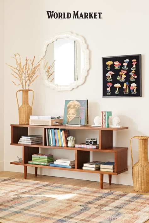 Featuring four roomy compartments, our bestselling mid-century-inspired Ashlyn bookcase offers ample storage space for books, framed photos and keepsakes. A rich medium-walnut stain highlights the wood construction of this asymmetrical shelf that doubles as a console table. #WorldMarket Bookshelf World, Earthy Mid Century Modern, Bookshelf Console, Open Console, Unique Living Room Furniture, Console Shelf, Wood Bookshelf, Unique Living Room, Wood Bookshelves