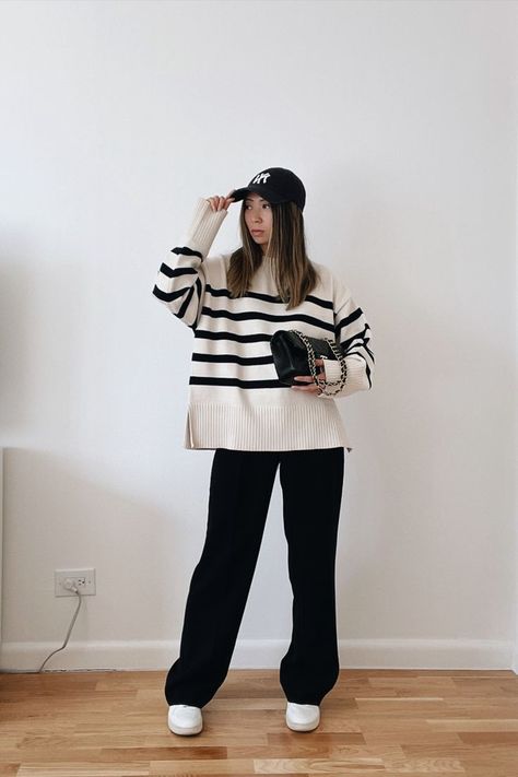 New york city based fashion influencer Lauren Lora wearing a casual cold weather outfit. She’s wearing a black and white oversized striped sweater, black wide leg trousers, white sneakers, a yankees hat and a black chanel classic flap. How To Style A Vest, Striped Sweater Outfit, Oversized Striped Sweater, Cold Weather Outfit, Classic Style Outfits, Pull Oversize, Black Wide Leg Trousers, Winter Fashion Outfits Casual, Stripe Outfits