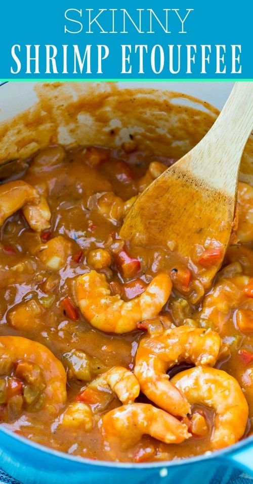 a blue pot filled with shrimp and sauce next to a wooden spoon on top of it