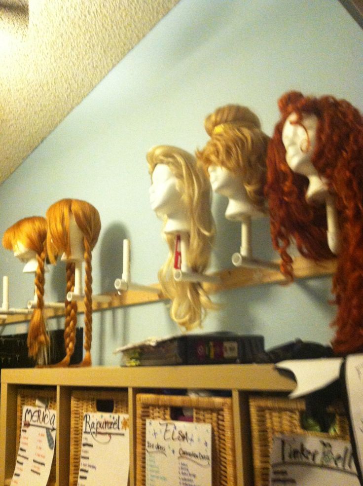 wigs are lined up on top of shelves in a room with posters and papers