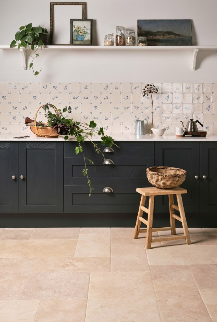 a kitchen with blue cabinets and plants on the counter top, along with a wooden stool