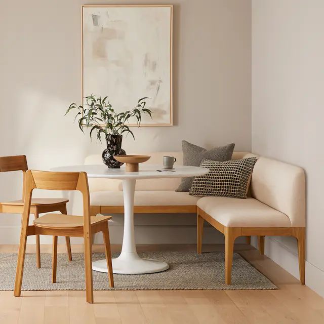 a white table with two chairs and a vase on it next to a couch in a living room