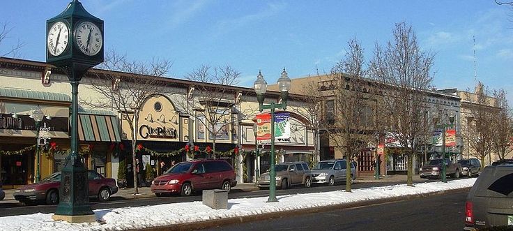 a street with cars parked on the side of it and a clock tower in the middle