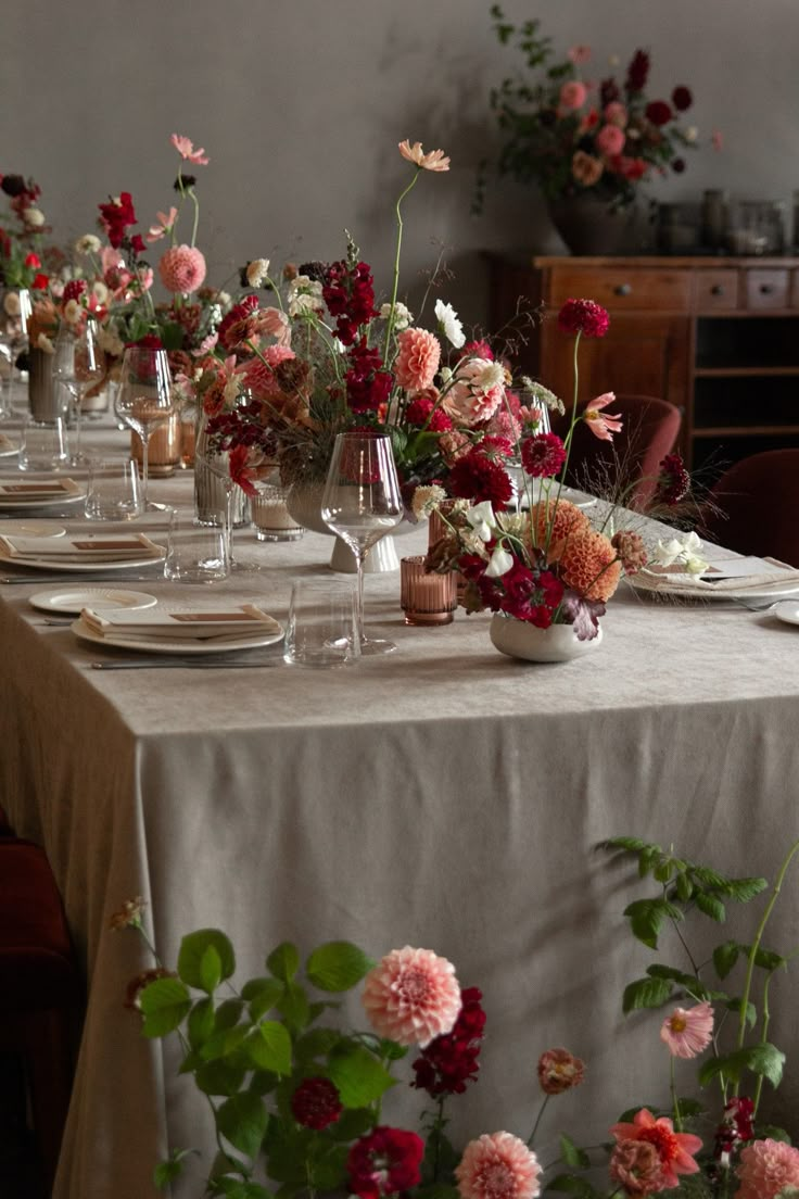 a long table is set with flowers and wine glasses for an elegant dinner party or celebration