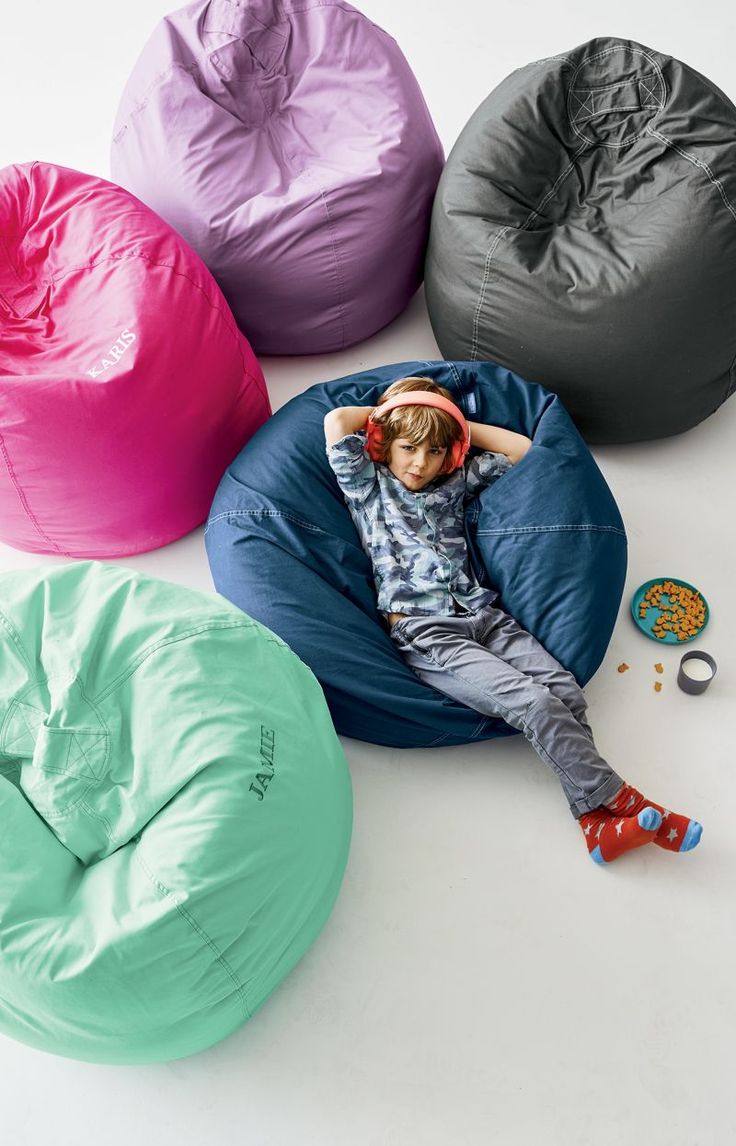 a young boy laying on a bean bag chair in four different colors and sizes,